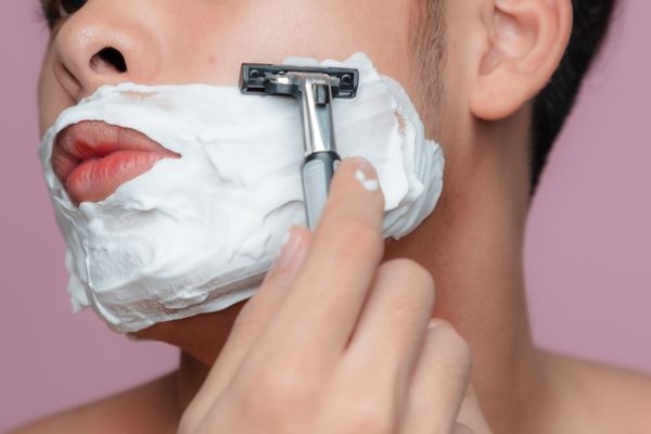 man shaving face with safety razor
